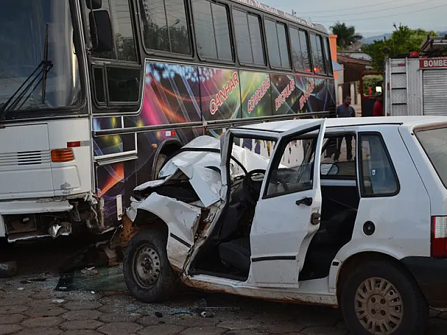 Após bater em ônibus estacionado, motorista de Uno fica preso às ferragens