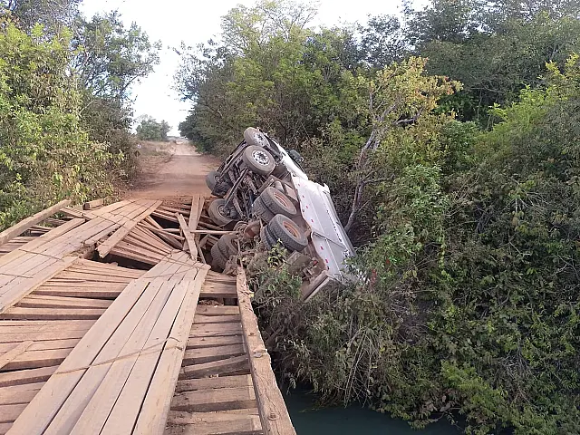 Caminhão carregado com pedriscos fica pendurado em ponte