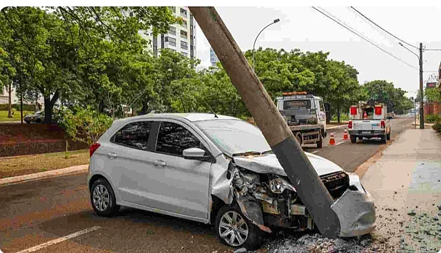 Carro bate em poste que fica pendurado em fiação e árvore