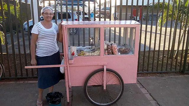 Vendedora chama atenção e conquista clientes pela simpatia e pelo carrinho rosa de pipocas